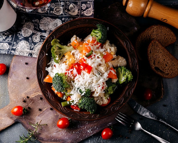 Widok z góry danie warzywne, w tym brokuły czerwone pomidory i ryż na szarej podłodze