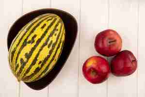 Bezpłatne zdjęcie widok z góry dojrzałych czerwonych jabłek z melonem kantalupa na misce na białej powierzchni drewnianych