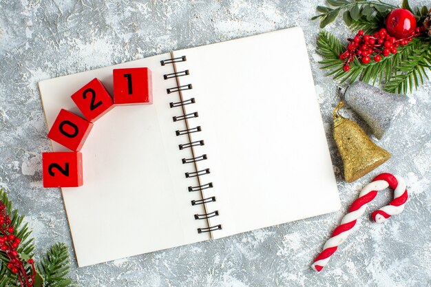 Widok z góry drewniane klocki na notatniku bożonarodzeniowe dzwonki i cukierki na szarym białym tle