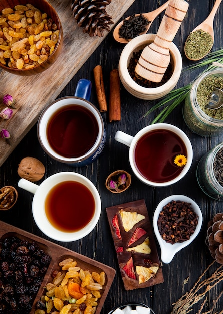 Widok z góry filiżanek herbaty i różnych przypraw i ziół z mieszanymi orzechami i suszonymi owocami na rustykalne