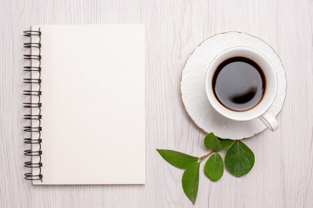 Widok z góry filiżanka herbaty z notatnikiem na białym biurku cukrowe ciasteczka herbaciane słodkie herbatniki