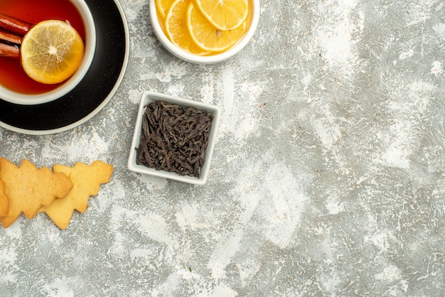 Widok z góry filiżanka herbaty z plasterkami cytryny i cynamonem miska herbatników z czekoladą na szarej powierzchni miejsce kopiowania