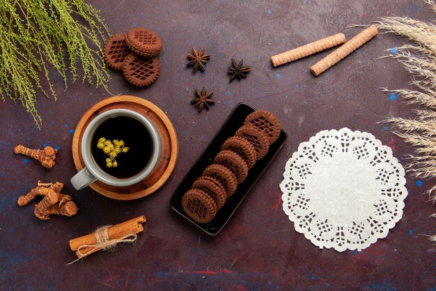 Widok z góry filiżankę herbaty wewnątrz płyty i filiżanki na ciemnym tle napój herbaciany kolor zdjęcie słodkie