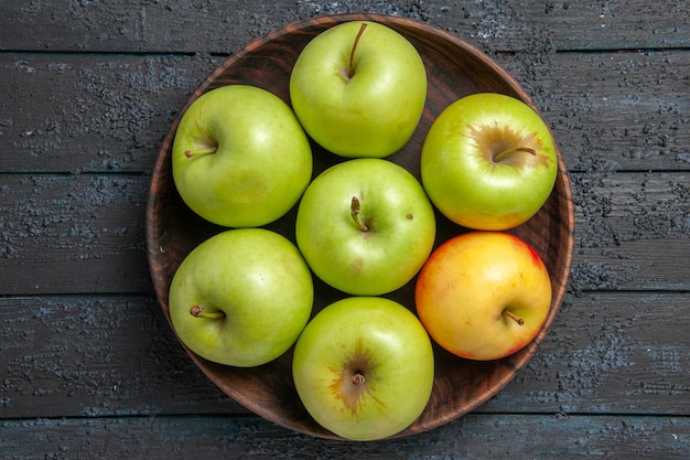 Bezpłatne zdjęcie widok z góry jabłka na stole miska siedmiu zielono-żółto-czerwonych jabłek na ciemnym stole