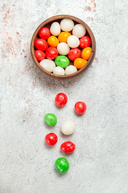 Widok z góry kolorowe cukierki na białym biurku w kolorze cukierkowej tęczy cukrowej