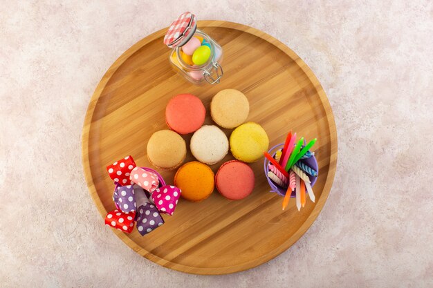 Widok z góry kolorowe francuskie makaroniki z cukierkami na różowym biurku ciasto cukrowe biszkoptowe słodkie