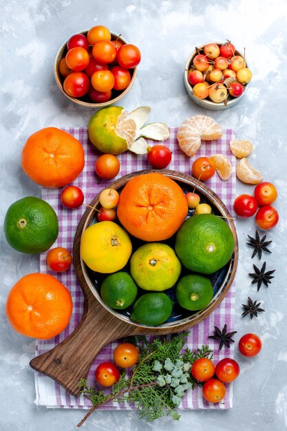 Bezpłatne zdjęcie widok z góry kwaśne świeże mandarynki z cytrynami i śliwkami na jasnym białym biurku