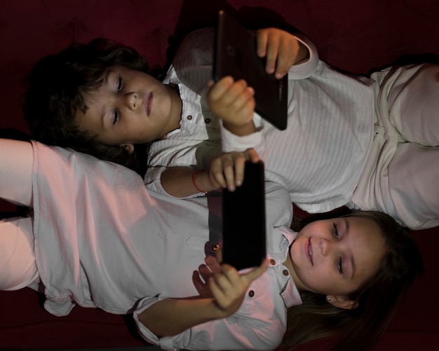 Bezpłatne zdjęcie widok z góry małego rodzeństwa grającego na swoich urządzeniach elektronicznych