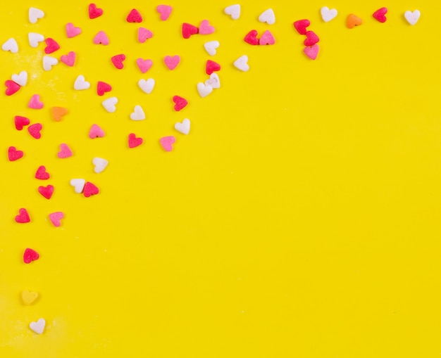 Bezpłatne zdjęcie widok z góry miejsca kopiowania wielobarwne cukierki w kształcie serca na żółtym tle