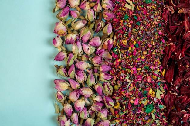 Widok z góry mieszanej herbaty ziołowej kwitnie płatki róż suszone pąki róż i zioła na niebiesko