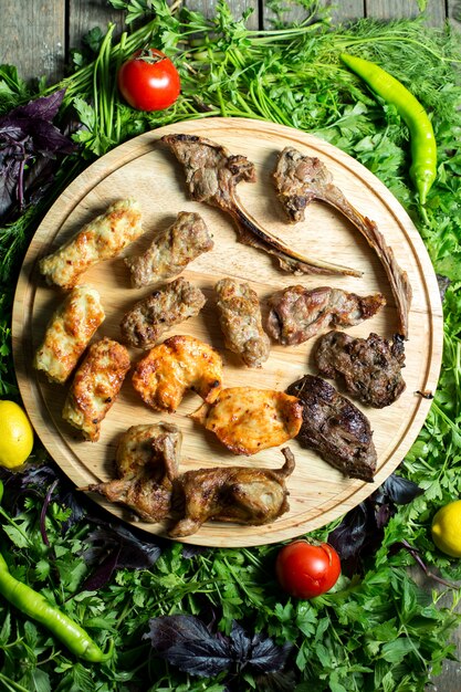 Widok z góry mieszanki kebab z grilla na drewnianym talerzu na świeże zioła
