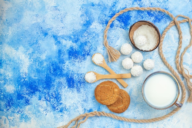 Widok z góry miska w proszku kokosowym i kulki kokosowe na niebieskim białym tle
