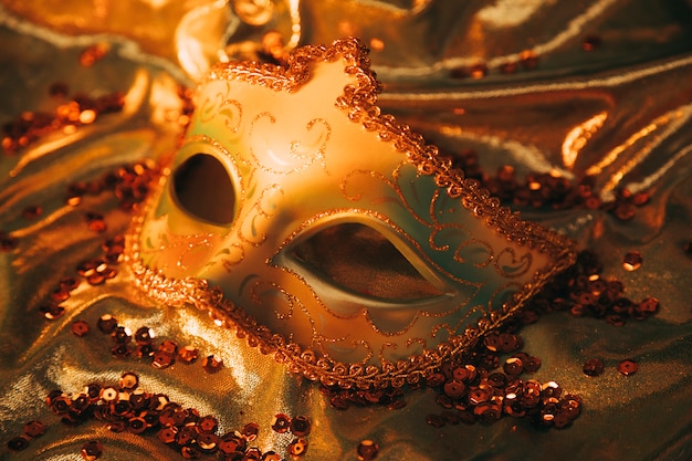 Widok z góry na eleganckie złote maski weneckie na złotym materiałem włókienniczym z cekinami