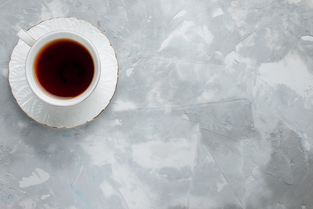 Widok z góry na filiżankę gorącej herbaty wewnątrz białej filiżanki na szklanej płycie na światło, słodki napój herbaciany