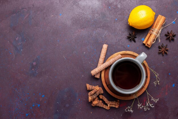 Widok z góry na filiżankę herbaty z cynamonem i cytryną na ciemnym biurku herbata słodka kolorowa fotografia