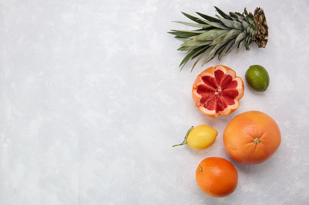 Widok z góry na owoce cytrusowe jako pomarańczowa cytryna mandarynka pokrojona w limonkę grejpfrut z liśćmi ananasa na białym tle z miejscem na kopię
