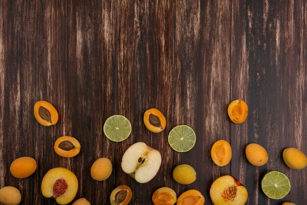 Widok z góry na plasterki limonki z morelami brzoskwiniowymi i jabłkiem na powierzchni drewnianych
