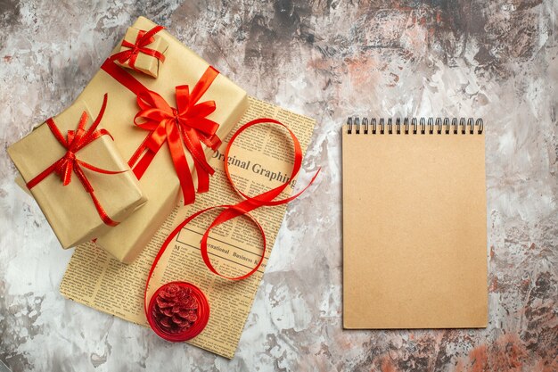 Widok z góry na prezenty świąteczne z czerwonymi kokardkami i notatnikiem na białym tle