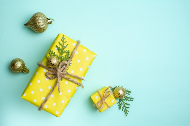 Widok z góry na świąteczne tło z żółtymi pudełkami prezentowymi w różnych rozmiarach i akcesoriami dekoracyjnymi na pastelowym zielonym tle