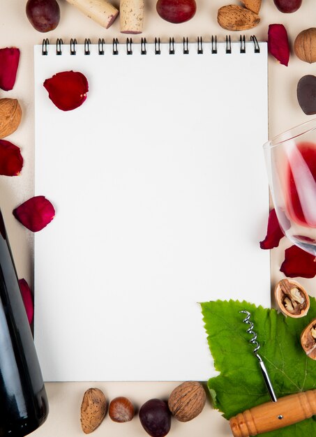 widok z góry notes z butelką czerwonego wina migdały orzechy korkociąg oliwki i płatki kwiatów wokół na białym tle z miejsca kopiowania