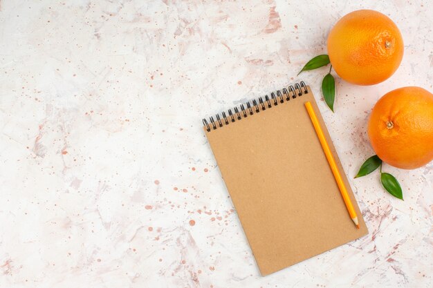 Widok z góry ołówkiem świeżych pomarańczy na notatniku na jasnej powierzchni z miejsca na kopię