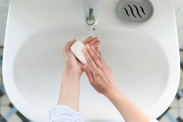 Widok z góry osoby myjącej ręce przy zlewie z mydłem
