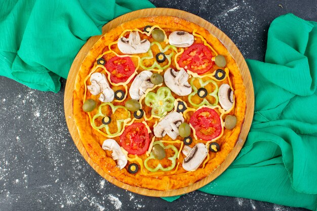 Widok z góry pizza grzybowa z czerwonymi pomidorami oliwki pieczarki pokrojone w środku z olejem na szarym biurku na szarym biurku ciasto na pizzę z zieloną tkanką włoskie