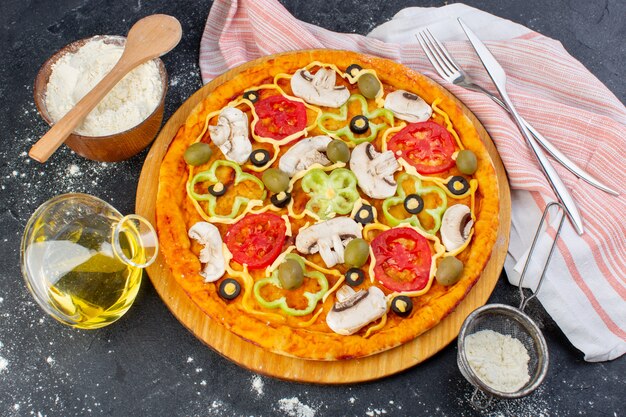 Widok z góry pizza grzybowa z czerwonymi pomidorami, papryką, oliwkami i grzybami, wszystkie pokrojone w oleju na ciemnym biurku, ciasto na pizzę z jedzeniem