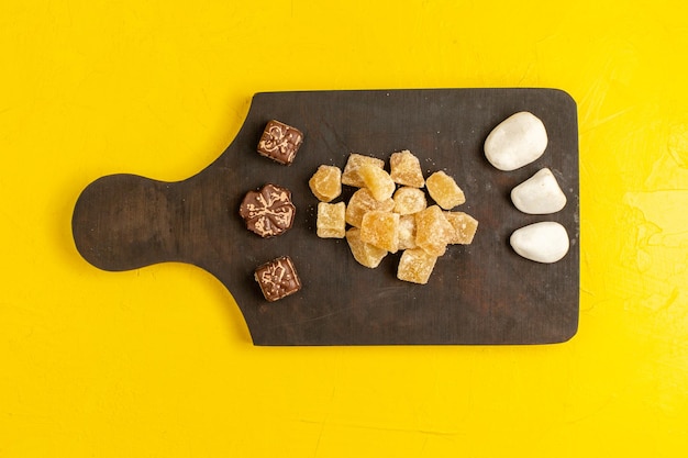 Bezpłatne zdjęcie widok z góry pokrojona marmolada słodka i pokrojona w cukier konfitury z czekoladą na żółtej powierzchni