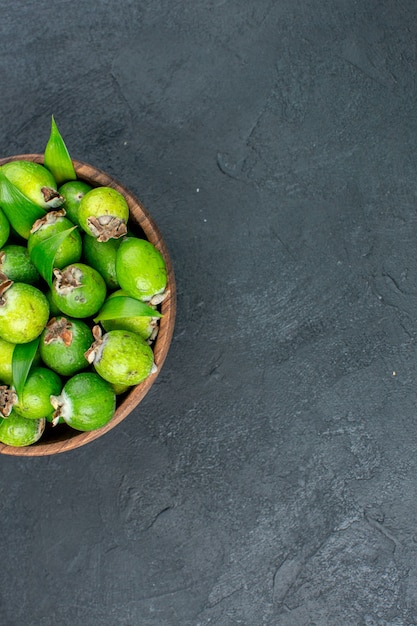 Widok z góry połowa świeżych feijoas w wiadrze na ciemnej powierzchni z miejsca na kopię