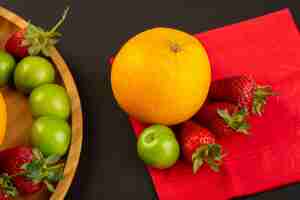 Bezpłatne zdjęcie widok z góry pomarańczowe wiśniowo-śliwkowe truskawki na czerwonej tkance izolowały łagodny dojrzały soczysty papkowaty witaminę