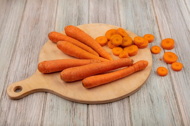 Bezpłatne zdjęcie widok z góry pomarańczowej marchwi warzyw korzeniowych na drewnianej desce kuchennej z posiekaną marchewką na szarej drewnianej powierzchni