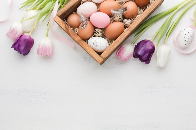 Widok z góry pudełka z jajkami na Wielkanoc i kolorowe tulipany