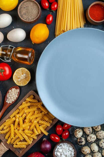 Widok z góry pusty talerz wokół jajek pomidorów przyprawy i włoskiego makaronu na ciemnym tle kolor jedzenie posiłek warzywo kuchnia kuchnia