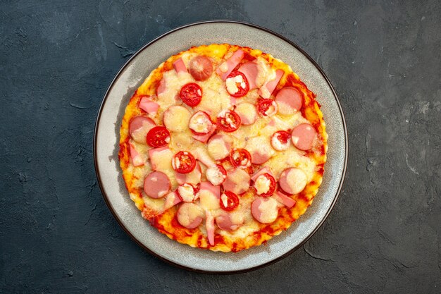 Widok z góry pyszna pizza z serem z kiełbaskami i pomidorami na ciemnym tle włoskie jedzenie ciasto ciasto fast-food kolor zdjęcia