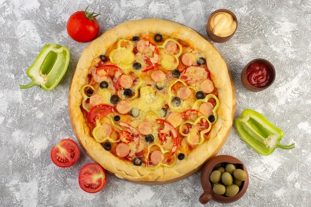 Widok z góry pyszna serowa pizza z kiełbaskami z oliwek i pomidorami na szarym biurku fast-food posiłek z włoskiego ciasta