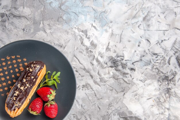 Widok z góry pyszne czekoladowe eklery z truskawkami na jasnej podłodze deserowe ciasto owocowe