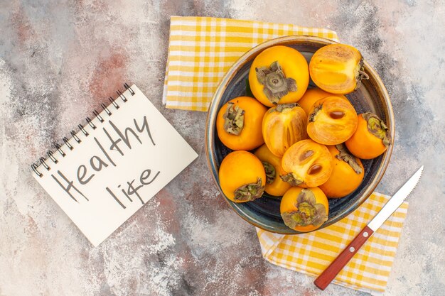 Widok z góry pyszne persimmons w misce na ręczniku kuchennym na nagim tle