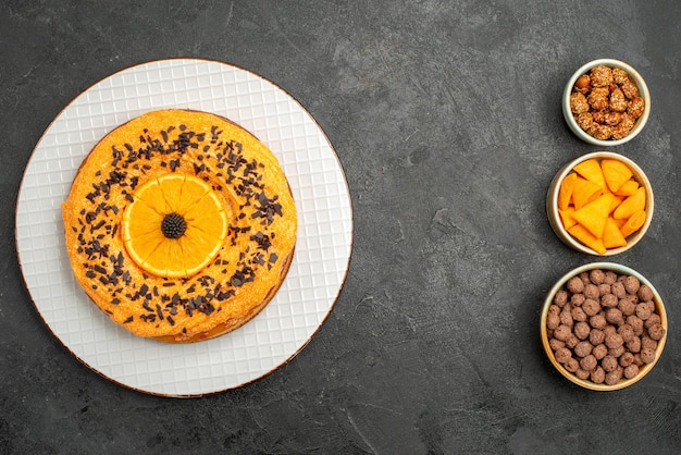 Widok z góry pyszne słodkie ciasto z pomarańczowymi plastrami na ciemnoszarej powierzchni ciasto deserowe ciastko z herbatą