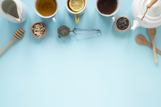 Bezpłatne zdjęcie widok z góry różnych rodzajów herbaty; miód; filtr; suche liście herbaty; czajniczek na niebieskim tle