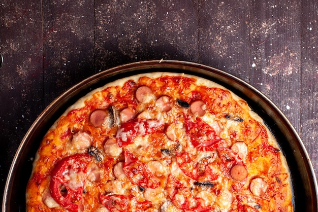 Widok z góry serowa pizza pomidorowa z oliwkami i kiełbaskami na patelni na brązowym, pizza food posiłek fast food ser kiełbasa