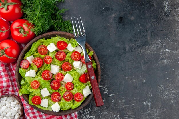 Widok z góry smaczna sałatka jarzynowa z pokrojonymi pomidorami serowymi i przyprawami na ciemnym tle posiłek jedzenie kolor dieta obiad zdrowie wolna przestrzeń
