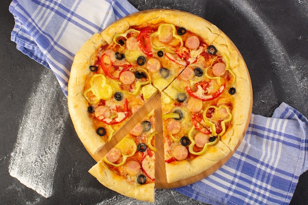 Widok z góry smaczna serowa pizza z czerwonymi pomidorami, czarnymi oliwkami i kiełbasami na ciemnym tle z ręcznikiem fast-food włoskim ciastem