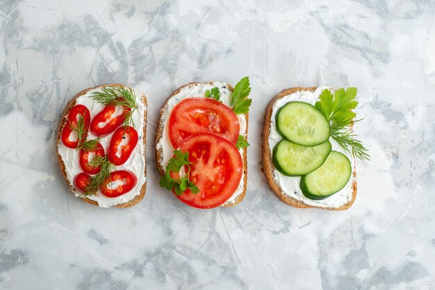 Widok z góry smaczne grzanki z pomidorami, papryką i ogórkami na białym tle kanapka chleb jedzenie posiłek obiad burger poziomy