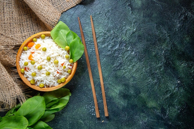 Widok z góry smaczny gotowany ryż z zieloną fasolką na ciemnym biurku