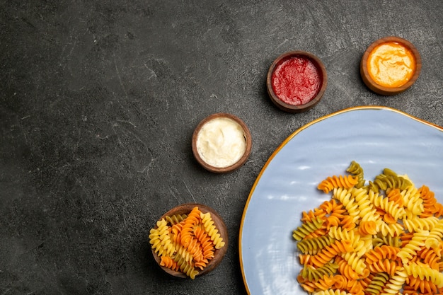 Widok z góry smaczny włoski makaron niezwykły gotowany spiralny makaron z przyprawami na szaro