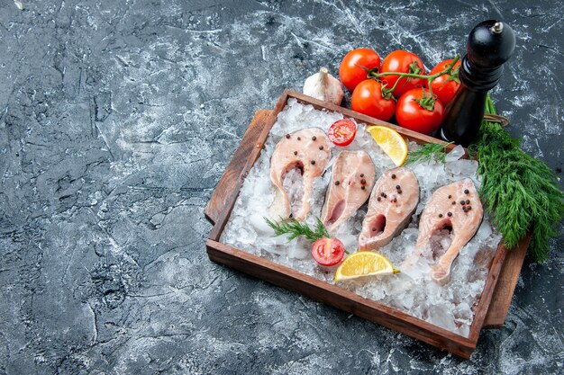 Widok z góry surowe plastry rybne z lodem na desce drewnianej pomidory czosnek koperek na stole miejsce kopiowania