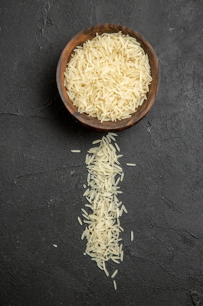 Bezpłatne zdjęcie widok z góry surowy ryż wewnątrz brązowego talerza na ciemnej powierzchni posiłek surowy ryż spożywczy