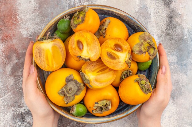 Widok z góry świeże persimmons feykhoas w misce w kobiecej dłoni na nagim tle