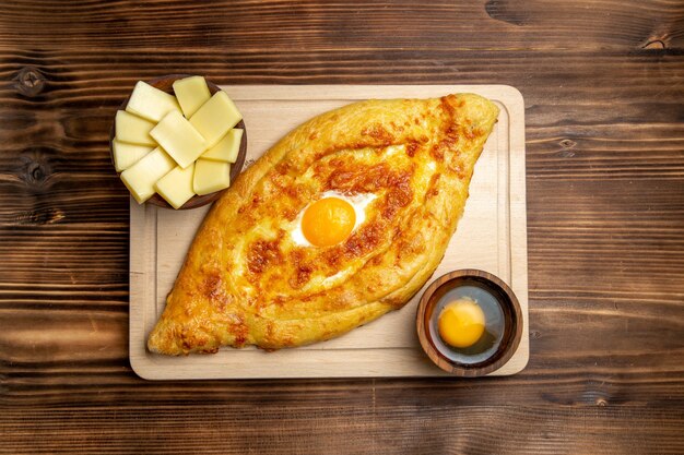 Widok z góry świeże pieczone pieczywo z gotowanym jajkiem na drewnianym biurku ciasto mąka bułka śniadanie jajka żywność